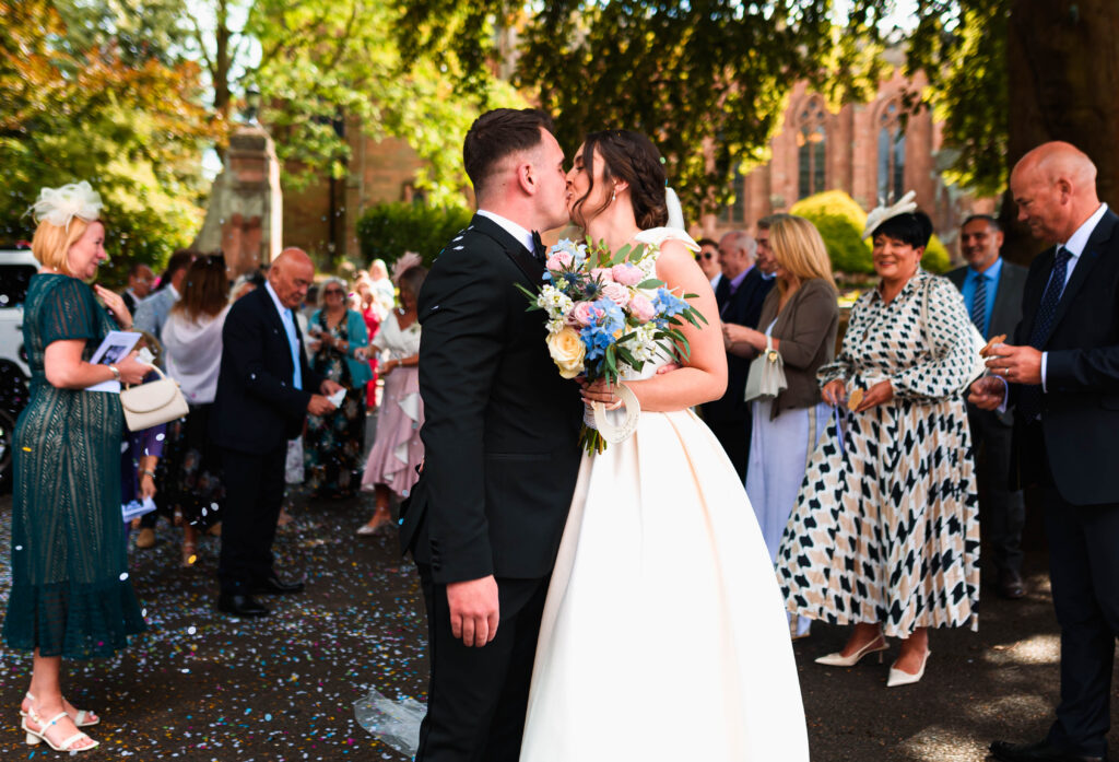 Couple on wedding day outside church with their guests